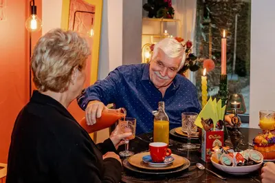 an older man and a woman sitting at a table at Sfeervolle B&B in de Voerstreek Lo-Ghis - met Zwembad in Voeren