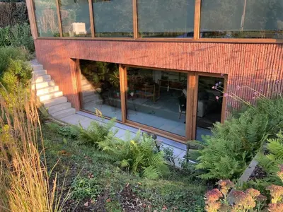 an external view of a building with glass windows and plants at Sweet Valley Cozy in Zutendaal