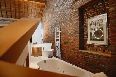 a bathroom with a brick wall and a bath tub at Art'lette Loft Balneo Bath & Infrared Sauna in Herve