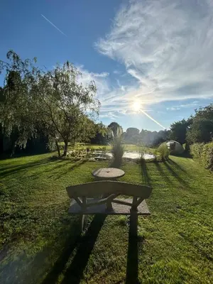a bench in a field with the sun in the sky at Le chalet Nord in Verviers