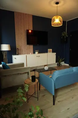 a living room with a blue couch and a tv at ChambreNchill in Seraing