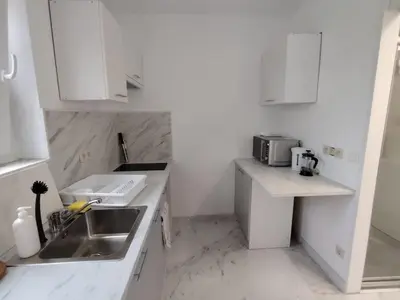 a white kitchen with a sink and a microwave at Spacious, warm and cozy studio in Heers