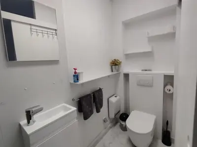 a white bathroom with a toilet and a sink at Spacious, warm and cozy studio in Heers