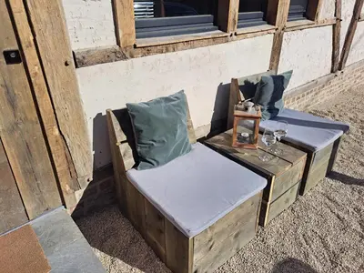 a wooden chair sitting outside of a building at Hoeve BôThé - Vakantiewoning in Alken