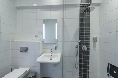 a white bathroom with a sink and a shower at Hotel De Boskar Pelt in Pelt