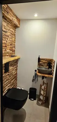 a bathroom with a black toilet and a brick wall at Comme chez Soi in Liège
