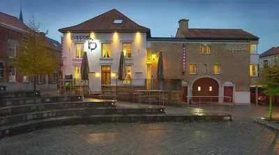 a building with tables and umbrellas in front of it at Klappoel - by Cafe Rene Borgloon in Borgloon