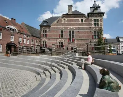 a woman sitting on a bench in front of a building at Klappoel - by Cafe Rene Borgloon in Borgloon