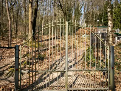 a metal gate in the middle of a forest at Holiday Home in Lanklaar near Forest Trails in Lanklaar