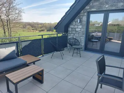 a patio with a couch and chairs on a balcony at L'Appart - New Appartement - Free Parking - Self Check-in - Terrasse in Eynatten