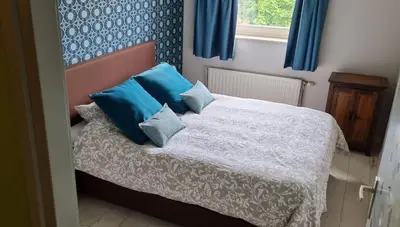a bedroom with a bed with blue pillows and a window at Take a break in Voeren