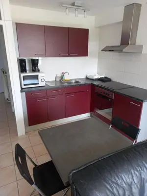 a kitchen with red cabinets and a black counter top at Ap78 Nature Ardennes Economy class apartment in La Calamine