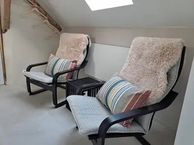 two chairs and a chair with pillows in a room at Hoeve BôThé - B&B in Alken