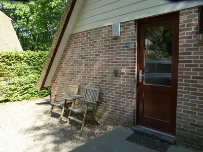 two chairs sitting next to a brick building with a door at De Onthaasting in Lanaken