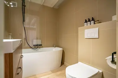 a bathroom with a tub and a toilet and a sink at Boshuisje Rekem - Azure in Lanaken