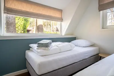 a bedroom with a bed with two pillows and a window at Boshuisje Rekem - Azure in Lanaken