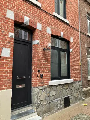 a black door on the side of a brick building at Huisje Emma in Tongeren