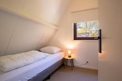 a small bedroom with a bed and a window at Boshuisje Rekem - Ember in Lanaken