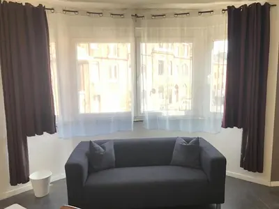 a living room with a couch and two large windows at Appartement confortable proche centre et idéal pour ULiège Sart Tilman in Liège