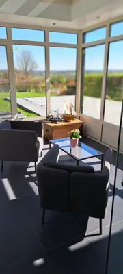 a living room with couches and a table and windows at Au coin du hérisson in Olne