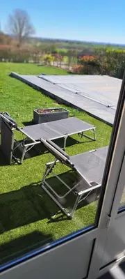 a table and chairs sitting on the grass next to a wing at Au coin du hérisson in Olne