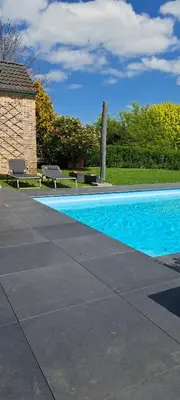 a swimming pool with two benches next to a building at Au coin du hérisson in Olne