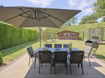 a table with chairs and an umbrella on a patio at Hesbein in Tongeren