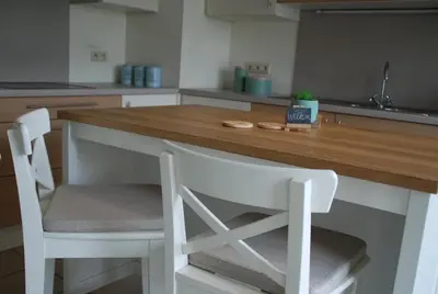 a kitchen with a wooden table and two white chairs at Vakantiewoning Huys op de Locht in Scherpenberg