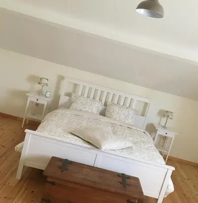 a white bed in a room with two tables at Vakantiewoning Huys op de Locht in Scherpenberg