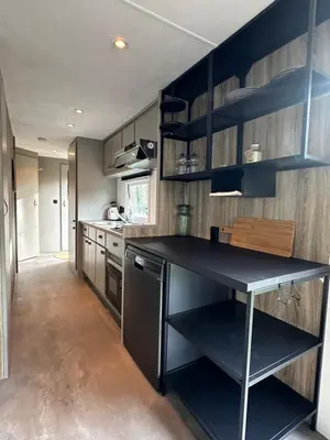 a kitchen with a black counter and wooden walls at Chalet Tibi in Bocholt
