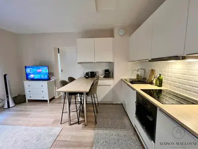 a kitchen with white cabinets and a table and chairs at Le coeur Liégeois - Hypercentre quartier piéton in Liège
