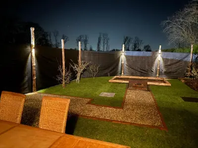 a garden at night with lights on a fence at House with garden, fireplace and hot tub in Kinrooi