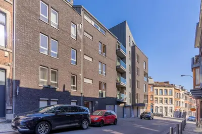 two cars parked in front of a brick building at Liège 3 Bedroom Apartment, Quiet and Central in Liège