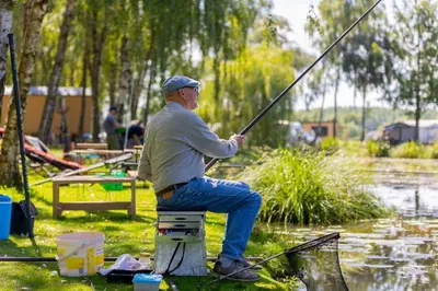 a man sitting on a block holding a fishing pole at Holiday home La Casetta in Kinrooi