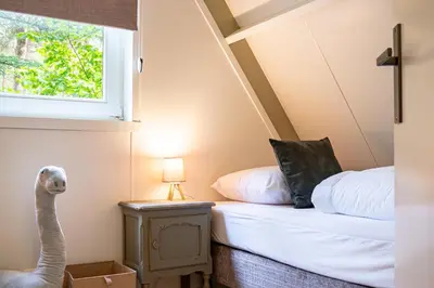 a small bedroom with a bed and a window at Boshuisje Rekem - Nilsson in Lanaken