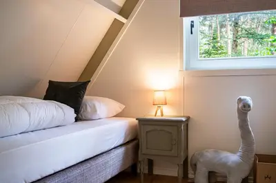 a bedroom with a bed and a toy ostrich next to a window at Boshuisje Rekem - Nilsson in Lanaken