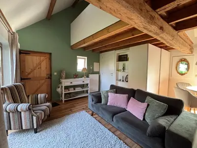 a living room with a blue couch and pink pillows at Bakhuisje Peer in Peer