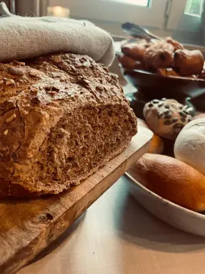 a loaf of bread on a wooden cutting board on a table at Guesthouse 't Goed Leven in Stokrooie