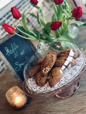 a plate of cookies on a table with a vase of flowers at Guesthouse 't Goed Leven in Stokrooie