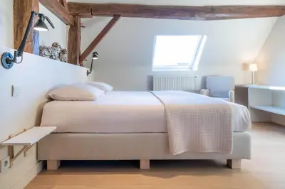 a bedroom with a large bed and a chair at Domein Marsnil in Heers