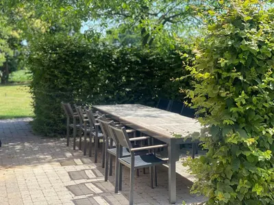 a wooden table and chairs sitting next to a hedge at 14 beds, 20p, 2 bath-, 1 livingroom in Houthalen-Helchteren