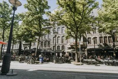 a group of people sitting at tables in front of a building at 1 bedroom apartment in Liège center, Place du Marche - 3rd floor in Liège