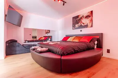 a bedroom with a large bed with a red ottoman at LoveRoom avec balnéo privative in Flémalle-Grande