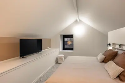 a white room with a large bed and a flat screen tv at Borgraaf - Palazzio in Borgloon