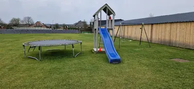 a playground with a blue slide in a yard at Basecamp18 in Lommel