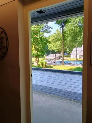 a sliding glass door with a view of a yard at Studio Eik 105 at the pool in nature domain in Houthalen-Helchteren