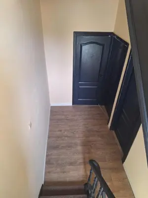 a hallway with a black door and a wooden floor at Maison sympa in Liège