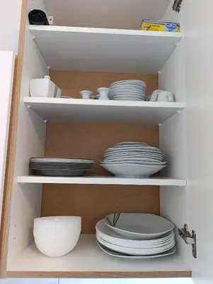 a cupboard filled with white plates and bowls at résidence KAKIKA in Verviers