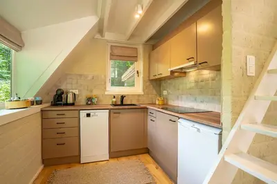 a kitchen with white cabinets and a staircase at Boshuisje Rekem - Kitoko in Lanaken