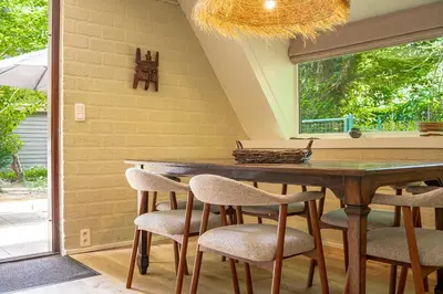 a dining room with a wooden table and chairs at Boshuisje Rekem - Kitoko in Lanaken